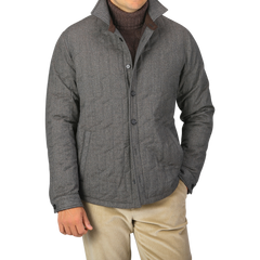 A person wearing a Maurizio Baldassari Taupe Beige Herringbone Quilted Virgin Wool Overshirt over a dark sweater and light-colored pants, with their hands partially in their pockets.