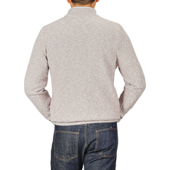 A person wearing a Maurizio Baldassari Beige Winter Wool Mouline 1/4 Zip Sweater and blue jeans stands facing away from the camera against a plain background.