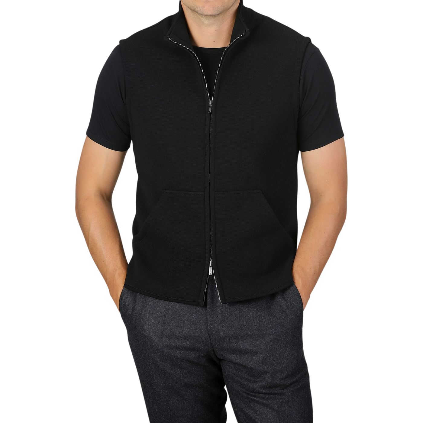 Here’s a revised version of the sentence incorporating the given product data:

A person wearing a black short-sleeve shirt under the Maurizio Baldassari Black Milano Stitch Wool Zip Gilet pairs it with dark gray pants, with hands partially in the pants pockets. The background is plain light gray.