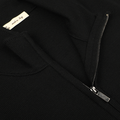 Close-up of the Black Milano Stitch Wool Zip Gilet by Maurizio Baldassari, crafted from virgin wool with a Milano stitch. A visible tag proudly states "Made in Italy." The zipper is partially undone, revealing the textured fabric.