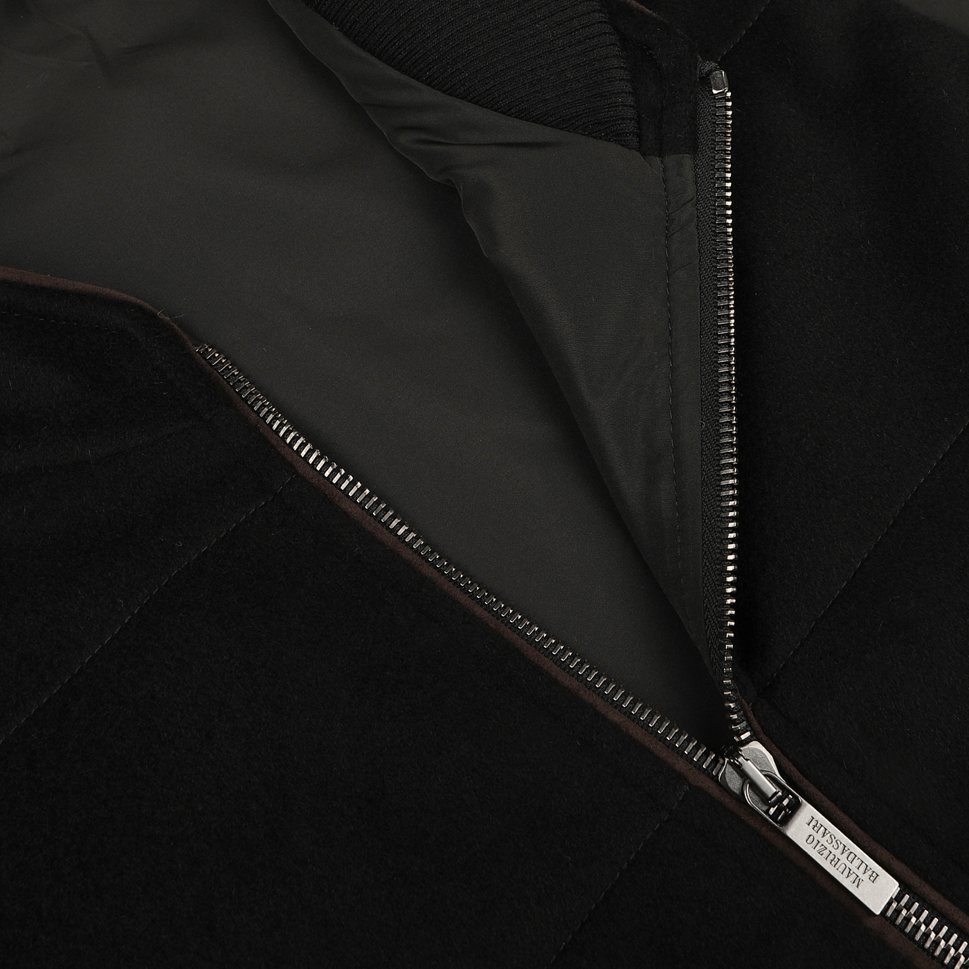 Close-up of a Maurizio Baldassari Black Water Repellent Cashmere Gilet's open zipper, revealing a luxurious inner cashmere lining and a small white tag attached to the zipper area.