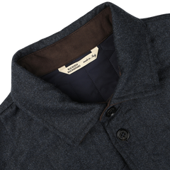 Close-up of a blue melange collared jacket with two buttons, featuring a label inside the collar that reads "Made in Italy." This Maurizio Baldassari overshirt is crafted from virgin wool and boasts sophisticated Thermore padding.