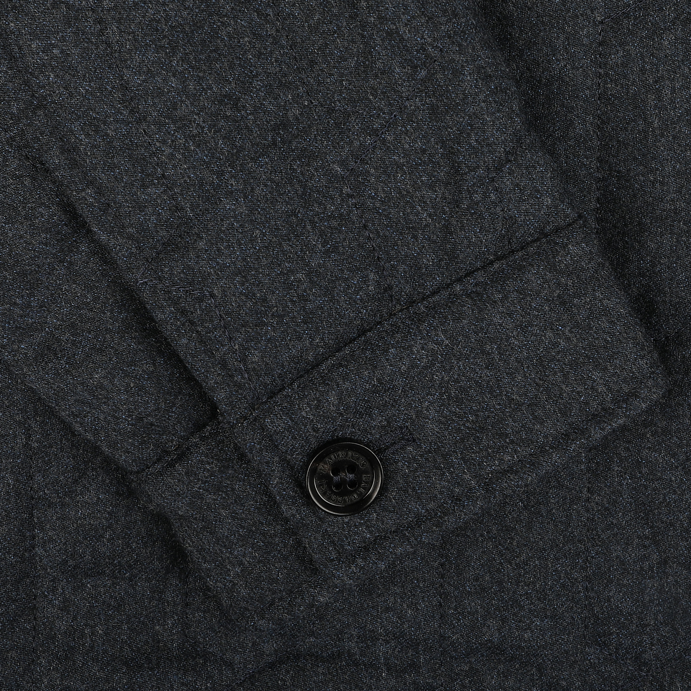 Close-up of a blue melange quilted virgin wool overshirt sleeve by Maurizio Baldassari, with a single black buttoned cuff and Thermore padding for added warmth.