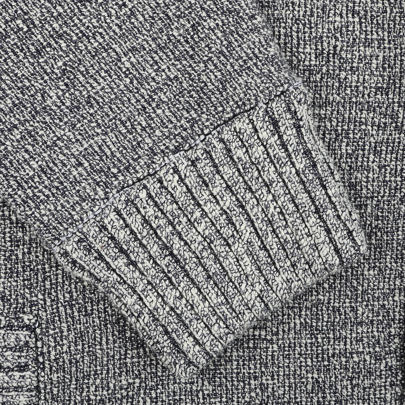 A close-up of the Blue Melange Summer Mouline Blouson by Maurizio Baldassari reveals a textured gray knit fabric with a ribbed cuff, highlighting detailed stitching and patterns that reflect the brand's exquisite craftsmanship.