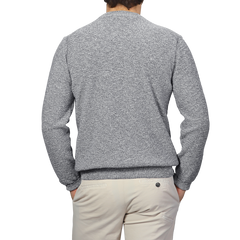 A person stands with their back to the camera, wearing a Blue Melange Summer Mouline Crew Neck Sweater and beige pants by Maurizio Baldassari.