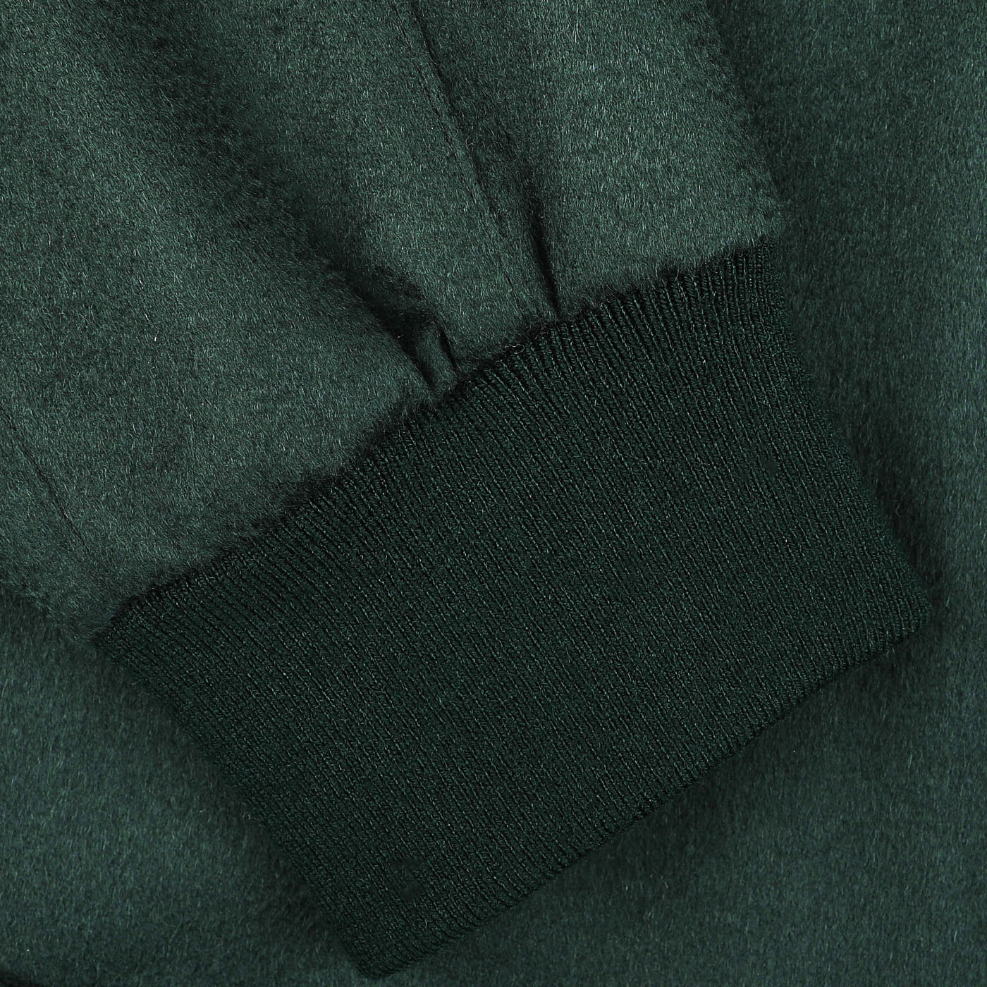 Close-up of a sleeve from the Maurizio Baldassari Bottle Green Cashmere Zip Blouson, featuring a ribbed cuff. The fabric texture appears soft and slightly fuzzy, reminiscent of cashmere outer layers.