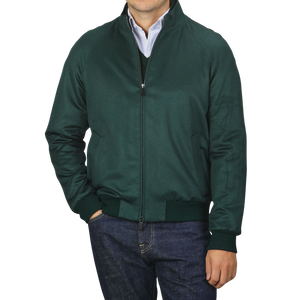 A person wearing a Maurizio Baldassari Bottle Green Cashmere Zip Blouson over a blue and white striped shirt and jeans. The person's hands are in the jacket pockets, and the jacket collar is slightly raised.