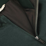 Close-up image of the Bottle Green Cashmere Zip Blouson by Maurizio Baldassari, showcasing a partially open metallic zipper and an interior label with "made in Italy" text.