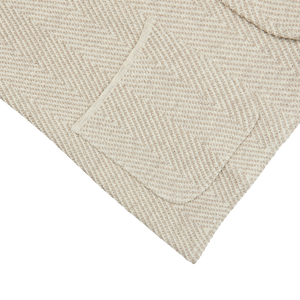 A beige herringbone towel with a pocket on it, featuring a Maurizio Baldassari Brown Herringbone Silk Cotton Linen Swacket pattern.