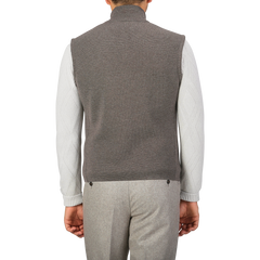 A person is seen from behind wearing the Brown Melange Milano Stitch Wool Zip Gilet by Maurizio Baldassari, a white long-sleeve shirt, and grey trousers made of pure virgin wool.