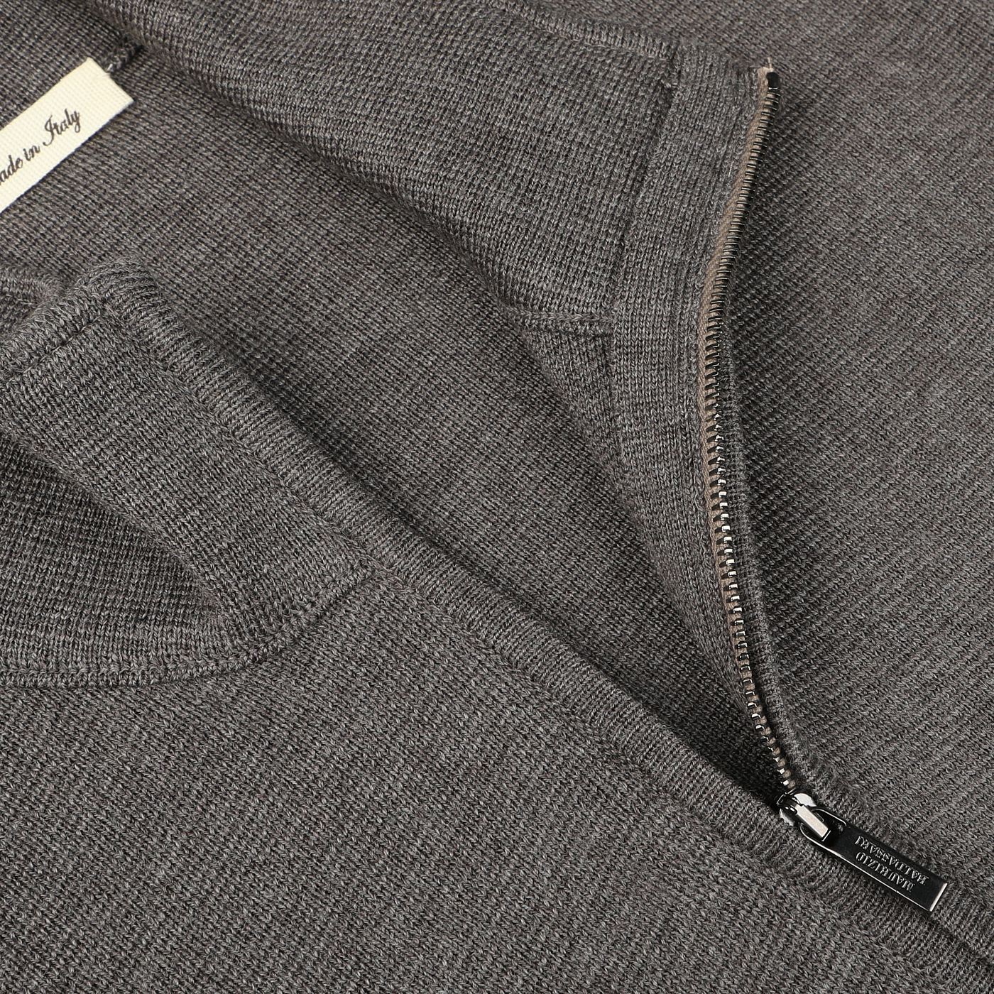 Close-up of a Brown Melange Milano Stitch Wool Zip Gilet by Maurizio Baldassari, featuring a half-zip design and a white label that reads "Made in Italy." The image shows the zipper partially opened.