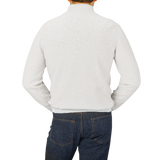 The back view of a man wearing jeans and a Maurizio Baldassari Cream White Cotton Mouline 1/4 Zip Sweater.