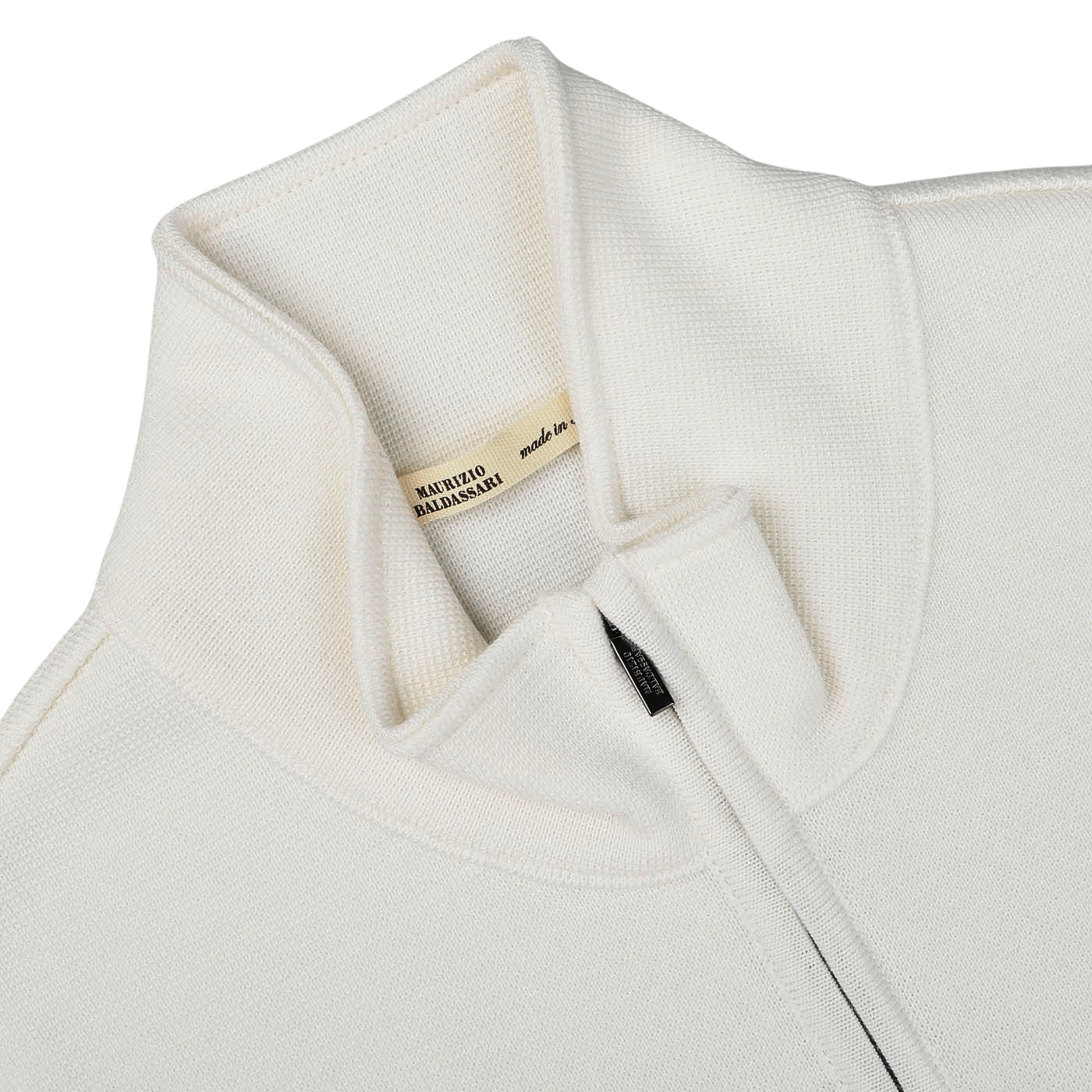 Close-up of the Cream Milano Stitch Wool Zip Gilet featuring a high collar and a zipped front, crafted with care. A beige label inside reads "MAURIZIO BALDASSARI made in Italy," reflecting its premium quality and design expertise.