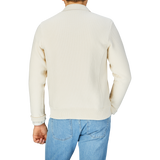 Rear view of a person wearing a Maurizio Baldassari Cream Beige Silk Cotton Knitted Blouson and blue jeans.