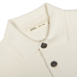 Close-up of a Cream Beige Silk Cotton Knitted Blouson collar and buttons with a label indicating "made in Italy" by Maurizio Baldassari.