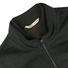 Close-up of a dark green water-repellent cashmere gilet with a ribbed collar, labeled "Maurizio Baldassari" inside, made from 100% cashmere.