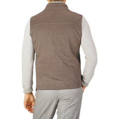 A person is seen from the back, wearing a Maurizio Baldassari Dark Taupe Water Repellent Cashmere Gilet over a light gray long-sleeve shirt and gray pants.