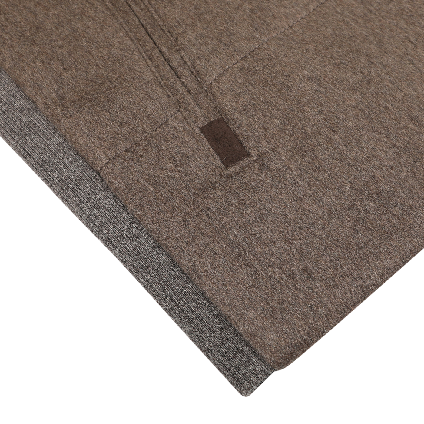 Close-up of a folded fabric with a visible seam, featuring a small brown tag and the luxurious feel of cashmere, showcasing the Dark Taupe Water Repellent Cashmere Gilet by Maurizio Baldassari.