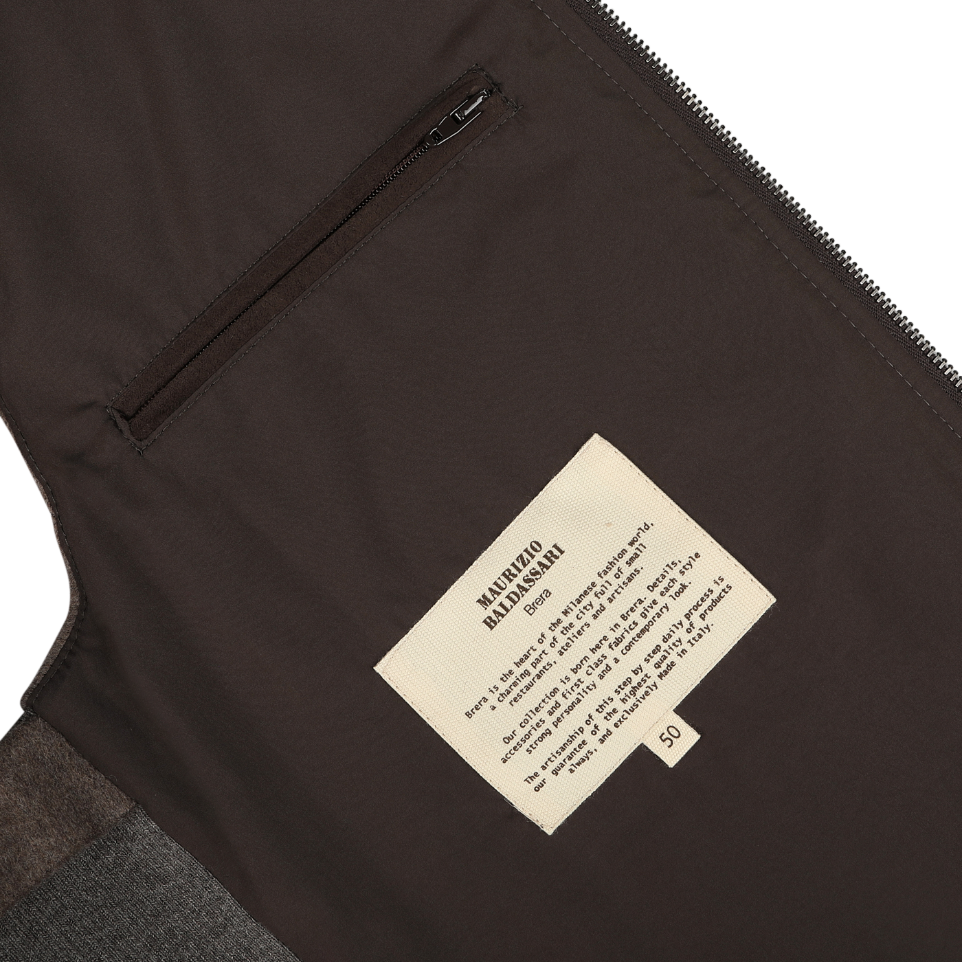 Close-up of the Dark Taupe Water Repellent Cashmere Gilet interior featuring a zippered pocket, a beige label with instructions and information, and crafted from luxurious cashmere by Maurizio Baldassari.