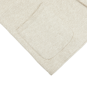 A white towel with a Light Brown Cotton Mouline Swacket pocket on it by Maurizio Baldassari.