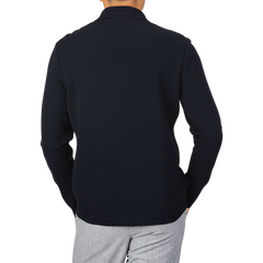 A person wearing a long-sleeved, Navy Blue Wool Milano Knitted Overshirt by Maurizio Baldassari and light gray pants, photographed from the back.