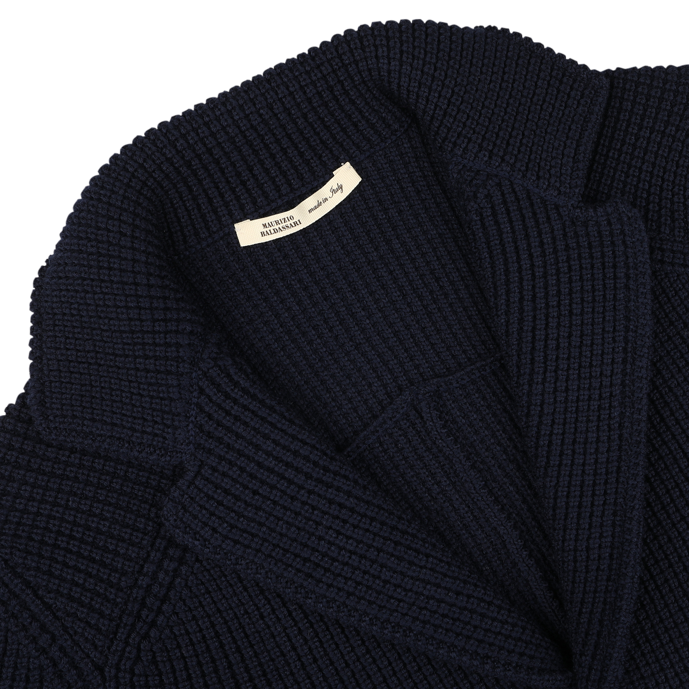 Close-up of a folded, Navy Blue Zegna Baruffa Wool Brenta Jacket by Maurizio Baldassari, with a visible white clothing label, showcasing exceptional craftsmanship rooted in Italian tradition.