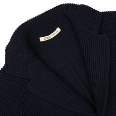 Close-up of a folded, Navy Blue Zegna Baruffa Wool Brenta Jacket by Maurizio Baldassari, with a visible white clothing label, showcasing exceptional craftsmanship rooted in Italian tradition.