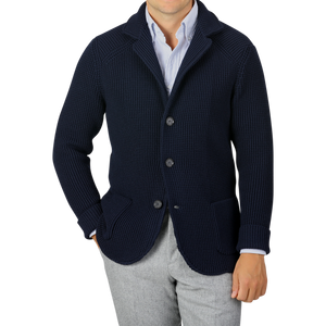 A person wearing a Maurizio Baldassari Navy Blue Zegna Baruffa Wool Brenta Jacket over a white and blue striped shirt and gray trousers, showcasing exceptional craftsmanship. The face is not visible.