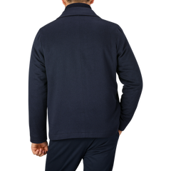 A person is seen from behind, wearing a Maurizio Baldassari Navy Cashmere Half Padded Chore Coat and dark blue pants against a plain gray background.