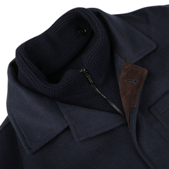 Close-up of the Navy Cashmere Half Padded Chore Coat by Maurizio Baldassari, featuring a high ribbed collar, a partially open zipper, and a brown suede accent near the lapel. The inclusion of Thermore technical down ensures optimal warmth and comfort.