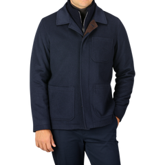 A person is wearing a Navy Cashmere Half Padded Chore Coat by Maurizio Baldassari, featuring three pockets, over a sweater with the collar partially unzipped. The background is plain and neutral.