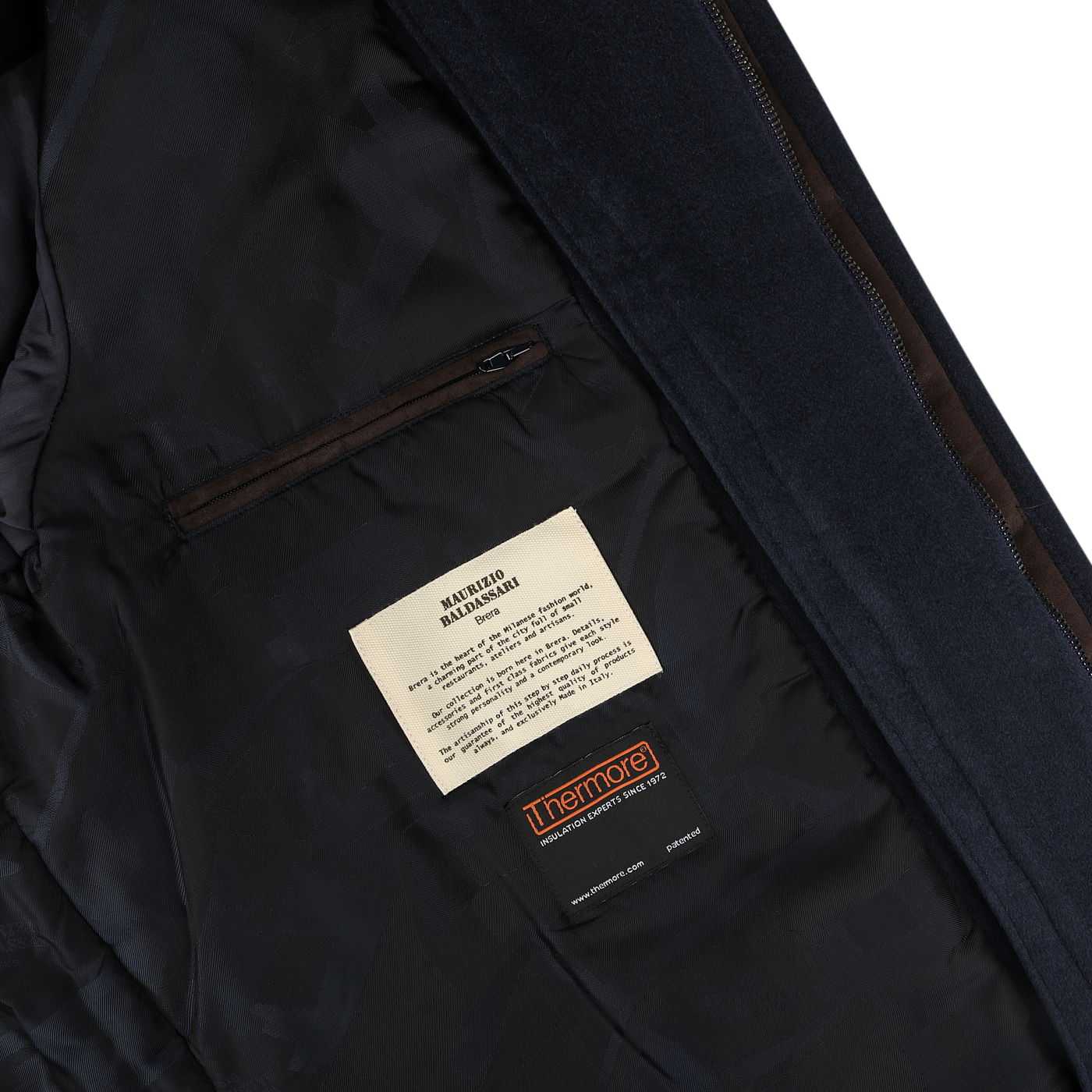 Close-up of the interior lining of the Navy Cashmere Half Padded Chore Coat by Maurizio Baldassari, featuring a zippered pocket and labels for machine wash instructions and Thermore insulation material.