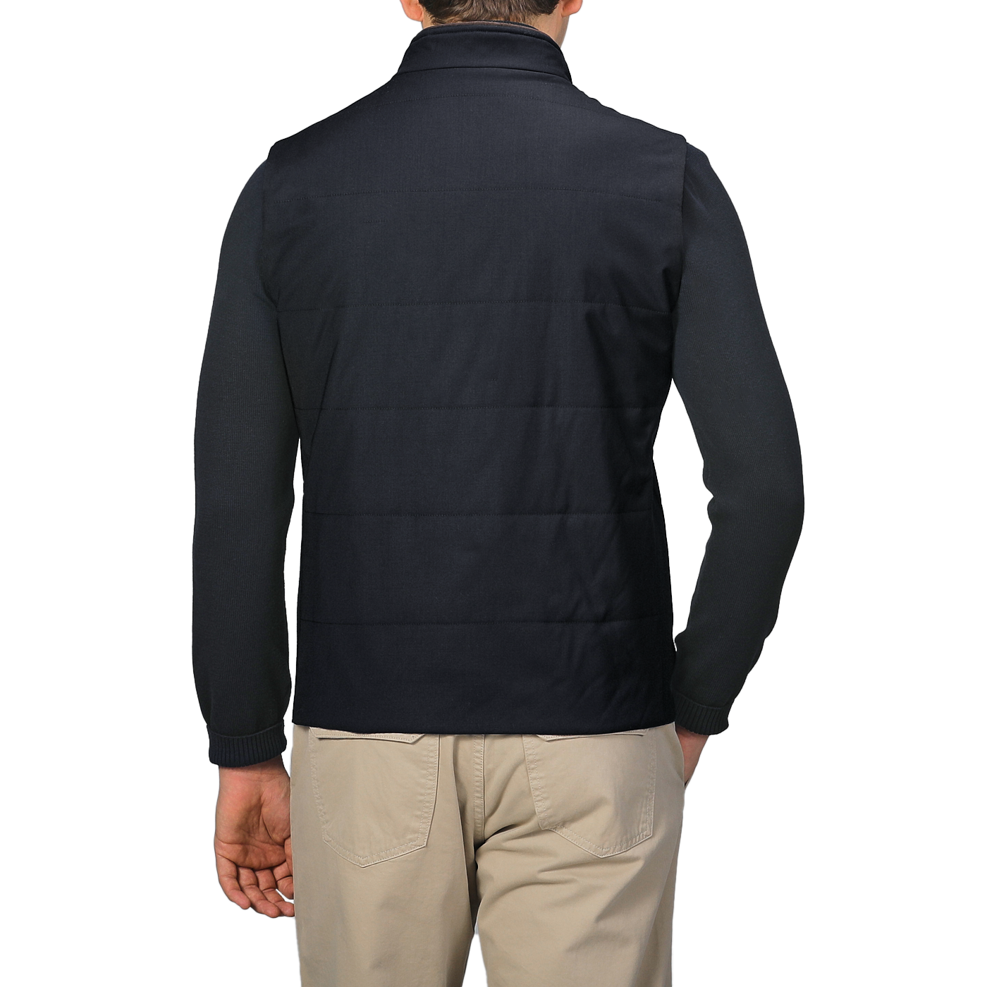 A person is seen from the back, wearing a Maurizio Baldassari Navy Merino Wool Thermore Travel Gilet and beige pants, set against a light gray background.