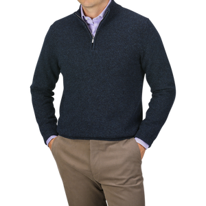 A person wearing a Maurizio Baldassari Navy Winter Wool Mouline 1/4 Zip Sweater over a light purple shirt, paired with light brown pants, stands with hands in pockets against a gray background.