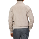 A person wearing a Maurizio Baldassari Oatmeal Beige Cashmere Zip Blouson with ribbed hems and gray trousers is seen from the back, standing against a plain background.