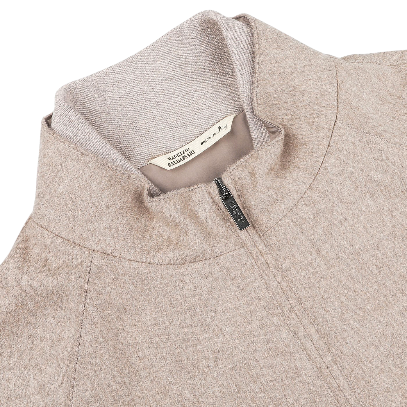 Close-up of an Oatmeal Beige Cashmere Zip Blouson jacket with a high collar by Maurizio Baldassari, featuring a label that reads "Made in Italy" and "Maglificio Gran Sasso." The fabric appears soft and textured, with ribbed hems for added detail.