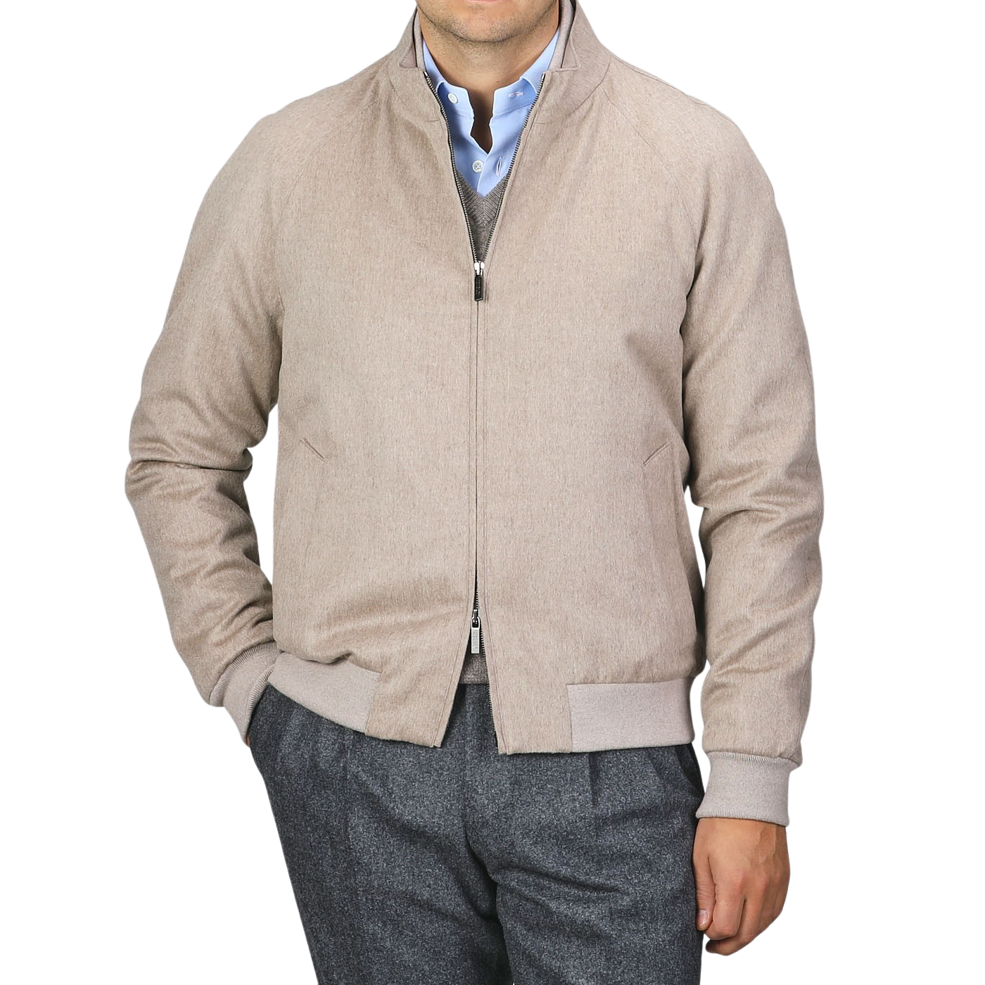 A person dressed in a Maurizio Baldassari Oatmeal Beige Cashmere Zip Blouson with their left hand in the pocket, wearing a blue button-up shirt and gray trousers against a plain background.