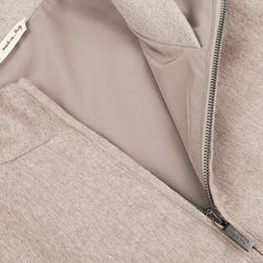 Close-up of an Oatmeal Beige Cashmere Zip Blouson by Maurizio Baldassari with a partially opened zipper and a white tag that reads "made in Italy." The inner lining and zipper details of the jacket are visible, along with the ribbed hems.