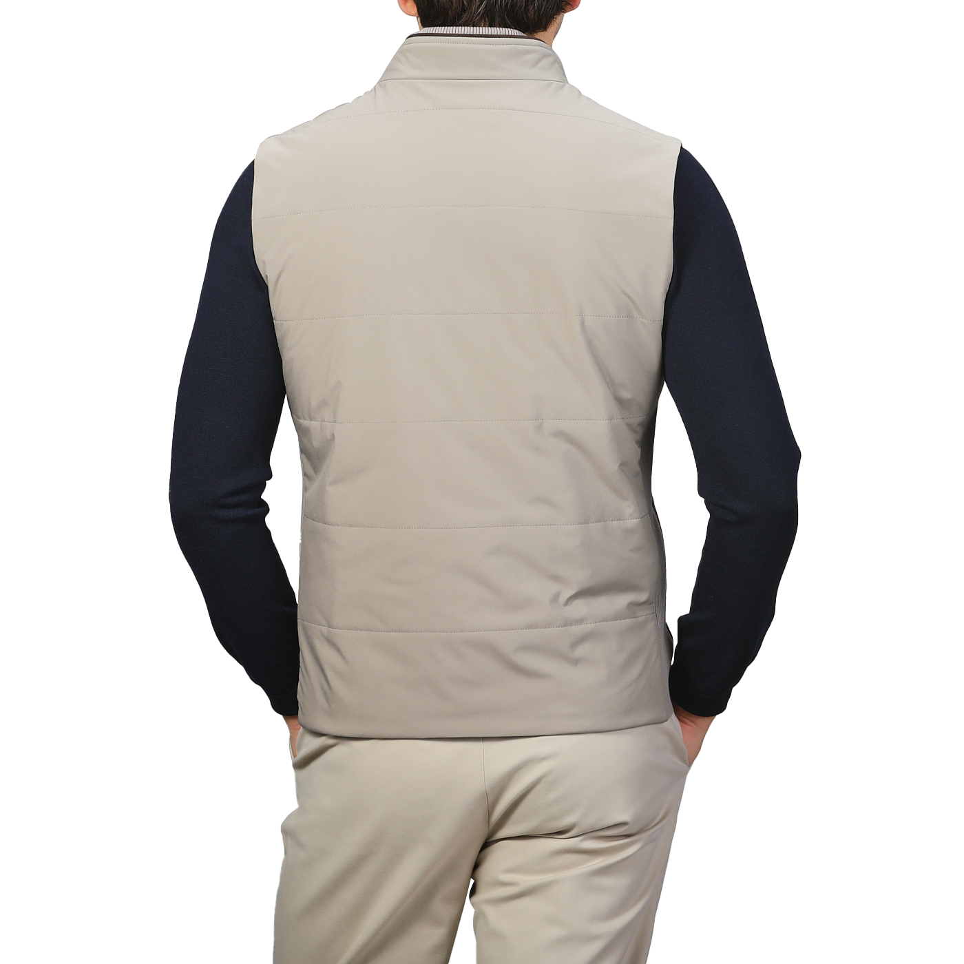 A person wearing a Maurizio Baldassari Pale Beige Nylon Thermore Travel Gilet, paired with beige pants and a navy long-sleeve shirt, seen from the back.