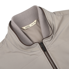 Close-up of a Pale Beige Nylon Thermore Travel Gilet by Maurizio Baldassari, featuring a ribbed collar and visible zipper. "Made in Italy" tag ensures lightweight comfort and style in this spring design.