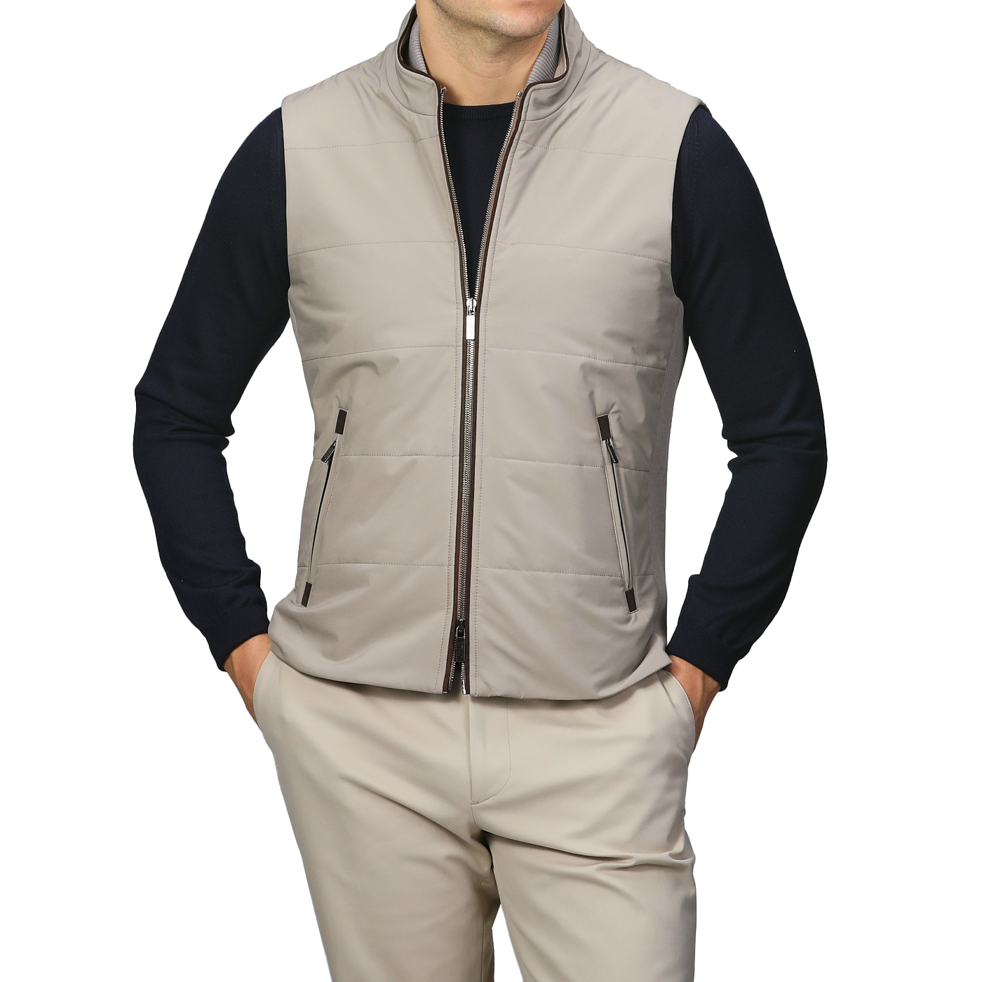 A person stands against a plain background, wearing the Maurizio Baldassari Pale Beige Nylon Thermore Travel Gilet over a black long-sleeve shirt and beige pants.