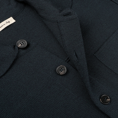 Close-up of a Petrol Green Milano Knitted Wool Overshirt by Maurizio Baldassari, showcasing its dark textured fabric crafted from virgin wool, with three black buttons and a partially visible label reading "Made in Italy.