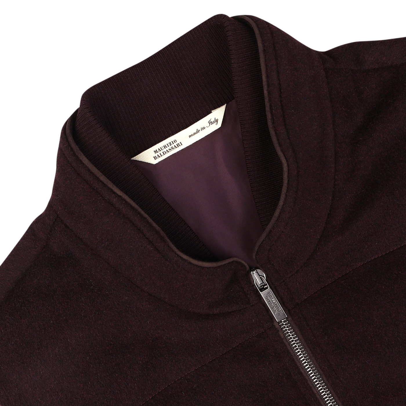 A close-up of a plum water-repellent cashmere gilet from Maurizio Baldassari, featuring a silver zipper and a label inside the collar that reads "Made in Italy." The fabric boasts 100% cashmere, offering luxurious comfort.