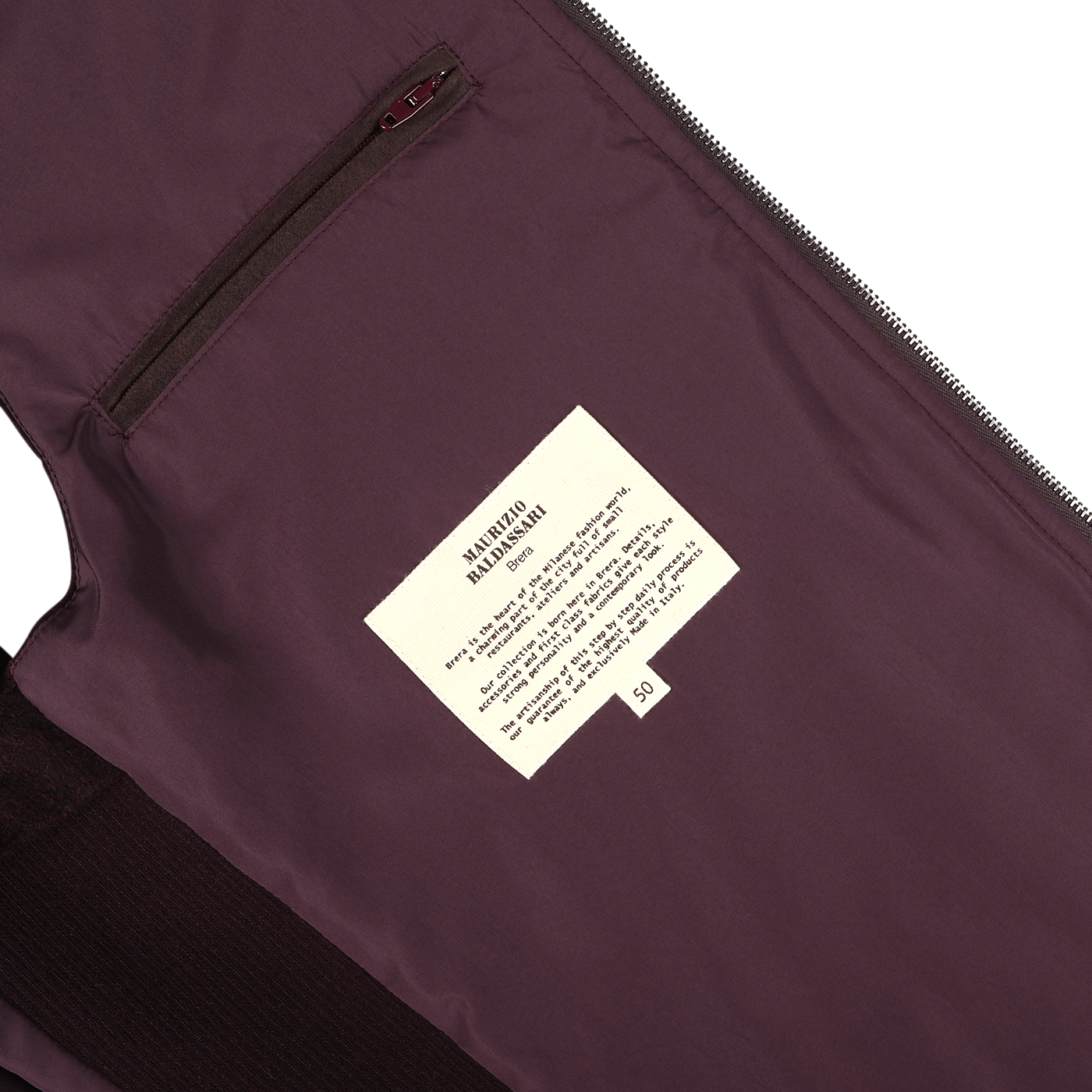 A close-up of the Maurizio Baldassari Plum Water Repellent Cashmere Gilet reveals its rich, dark purple hue. The interior label displaying care instructions is prominently featured, along with a small zippered pocket next to it.