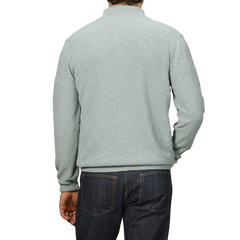 A person wearing a Maurizio Baldassari Sage Green Summer Mouline 1/4 Zip Sweater and dark jeans is shown from the back against a plain background.