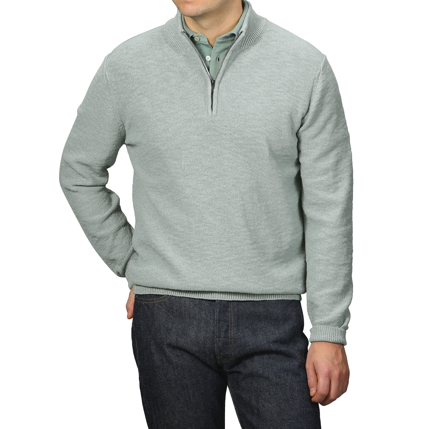 A person models the Sage Green Summer Mouline 1/4 Zip Sweater by Maurizio Baldassari over a green collared shirt and dark jeans, standing against a gray background.