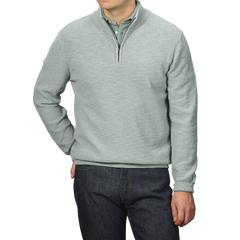 A person models the Sage Green Summer Mouline 1/4 Zip Sweater by Maurizio Baldassari over a green collared shirt and dark jeans, standing against a gray background.