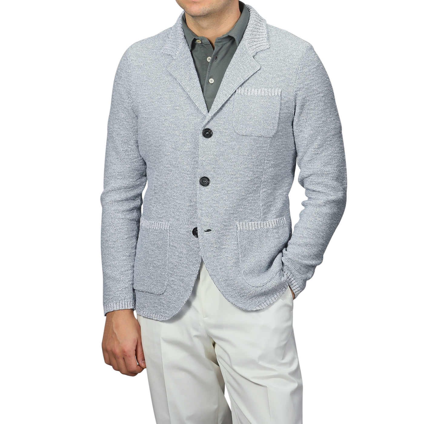 A man exudes relaxed luxury in the Sky Blue Summer Mouline Knitted Jacket by Maurizio Baldassari, paired with a dark gray collared shirt and white pants, one hand casually in his pocket. The cotton-viscose blend enhances sophistication against the plain background.