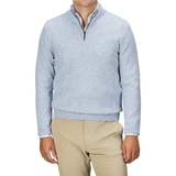 A person is shown from shoulders to waist, wearing a Sky Blue Winter Wool Mouline 1/4 Zip Sweater by Maurizio Baldassari and beige pants, against a plain background.