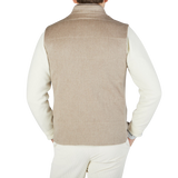 The back view of a man wearing a Maurizio Baldassari Beige Water Repellent Pure Cashmere Gilet in oatmeal beige.